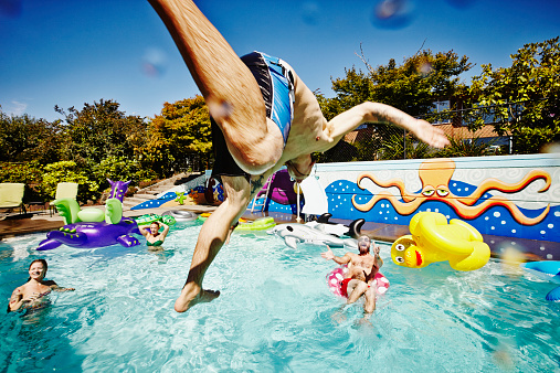 520749655-man-in-mid-air-jumping-into-pool-during-gettyimages