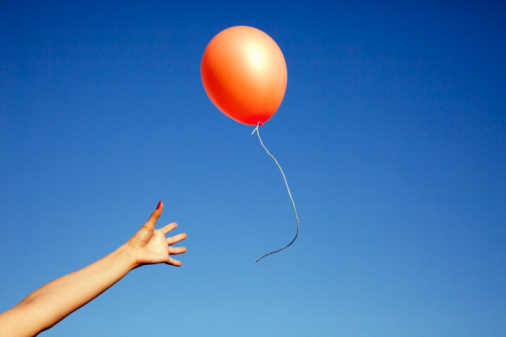 91538368-womans-arm-reaching-for-a-floating-balloon-gettyimages
